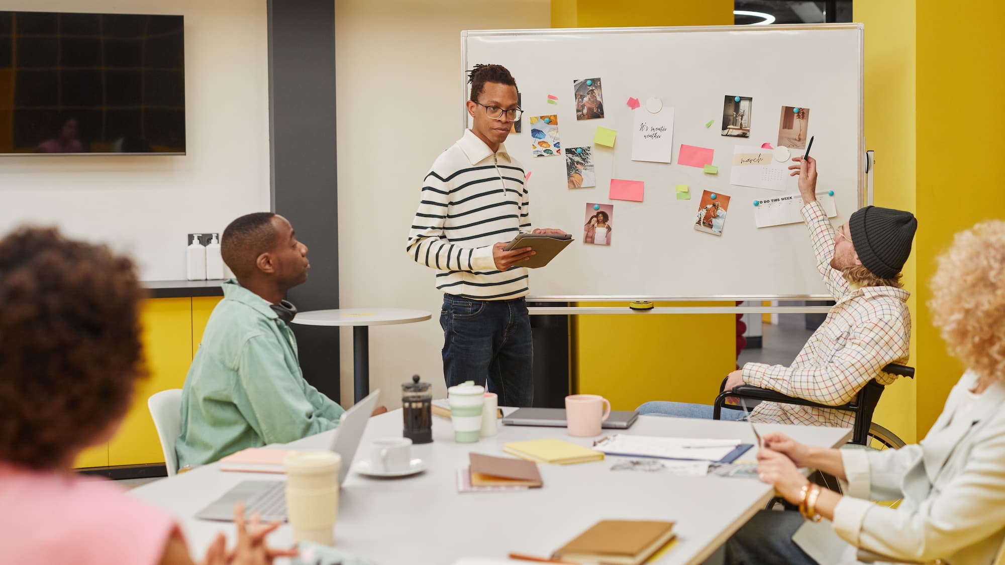 A practitioner leading a small working session at a whiteboard, walking a group through a plan in progress.